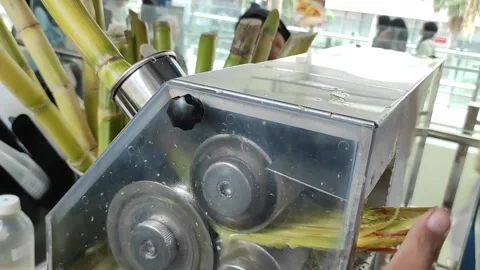 A seller is squeezing sugarcane using a machine Stock Footage 263582269