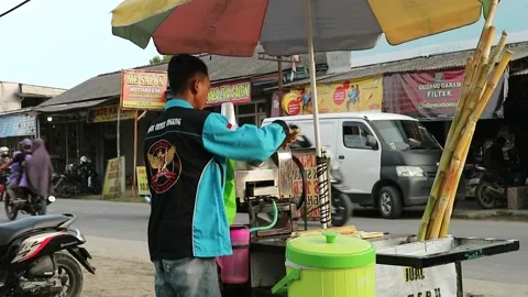 A seller of sugar cane ice preparing a customer's order on the side of the ro Stock Footage 239507330