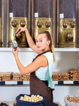 Seller woman is pouring coffee from containers in the alimentacion shop. Stock Photos
