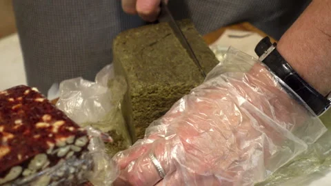 Seller's hands cut a piece of halva on the counter. Stock Footage 101474595