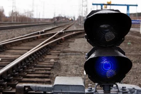 Semaphore with burning blue light. The intersection of railway tracks. Stock Photos