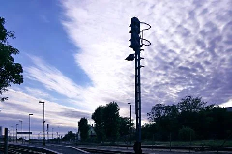 Semaphore on railway station in front of dramatic fleecy clouds sky Stock Photos