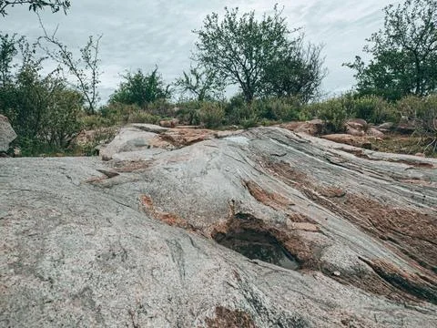 Semi-arid landscape featuring a large rock formation. Stock Photos