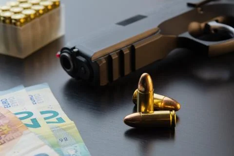 Semi-automatic pistol, bullets and Euro banknotes laid out on black table Stock Photos