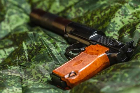Semi-automatic silenced pistol on pixel camouflage background Stock Photos