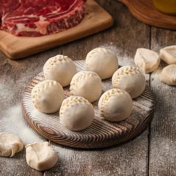Semi finished manti dumplings on board with flour Stock Photos