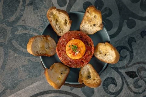 Semi-prepared beef tartar with egg yolk, spices and with toasted bread Stock Photos