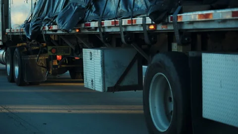 Semi-truck with loaded open deck trailer is traveling on a highway at golden 库存影片 322087841