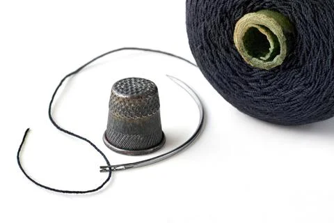 Semicircular needle with black thread and spool and vintage old thimble iso.. Stock Photos