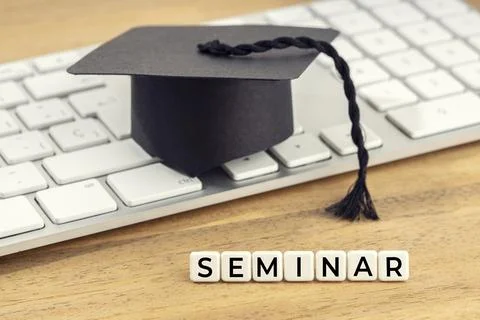 Seminar concept. Graduation cap on computer keyboard on wooden desk Stock Photos