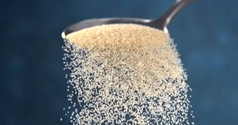 Semolina falling from a spoon in slow motion on blue background Stock Footage 346449731