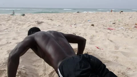 A Senegalese man making push-ups on the beach Stock Footage 276664752