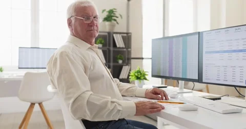 Senior accountant analyzing finance data at office desk with computer and Stock Footage 345018903