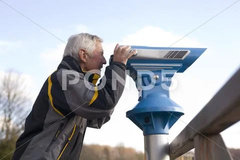 Senior adult man looking through telescope, side view Stock Photos
