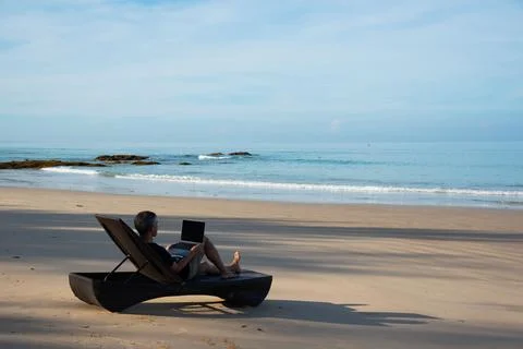 A senior adult using computer on the beach Stock Photos