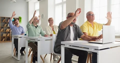 Senior adults raising hands in computer training class, engaged lifelong Stock Footage 340939093