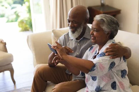 Senior african american couple sitting on sofa using smartphone taking selfies Stock Photos