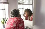 A Senior African American Woman Looking At Her Reflexion In The Mirror And Stock Photos
