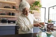 Senior African American Woman Preparing Tea In Kitchen Stock Photos