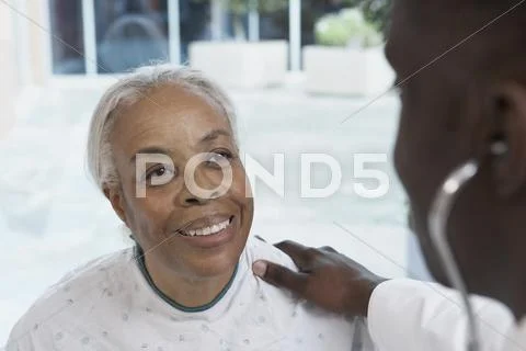 Senior African woman smiling at African doctor in hospital Stock Photos