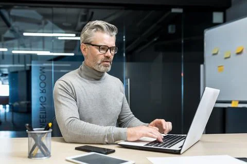 Senior and experienced programmer works in modern office at laptop, male web Stock Photos