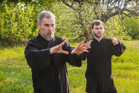 Senior and young guy do Qi Gong or Tai Chi exercise for relaxation and health Stock Photos