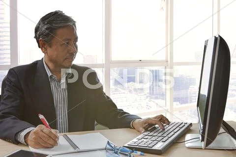 Senior asain business man writing and working on pc computor Stock Photos