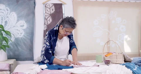 Senior Asian artisan writes pattern marks on cloth, measuring layout for resist Stock Footage 337219153