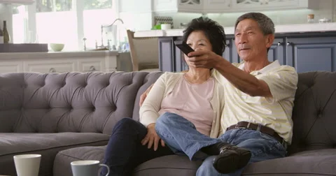 Senior Asian Couple At Home On Sofa Watching TV Shot On R3D Stock Footage
