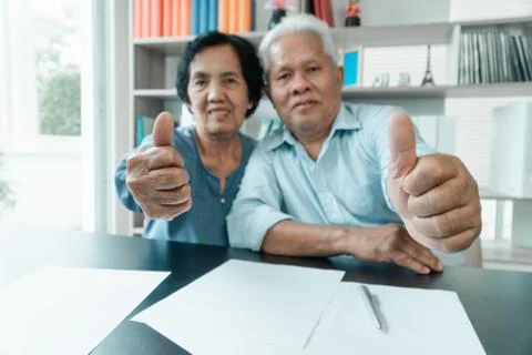 Senior Asian couple using the calculator and paperwork on desk at home to cal Stock Photos