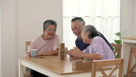 Senior Asian man and two women play wooden block stacking game at table Stock Footage 345055175