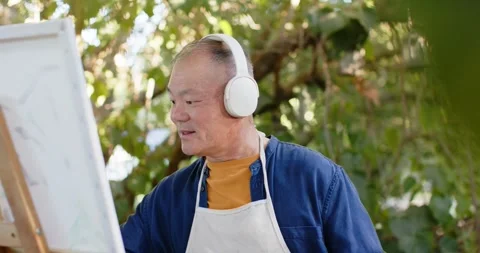 Senior Asian man studying canvas at easel outdoors with headset, mixing palette, Stock Footage 344949776