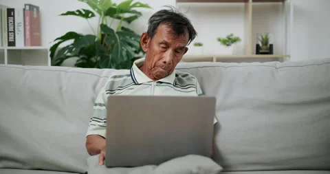 Senior Asian man using laptop while sitting on sofa in living room at home. Stock-Footage 316016745