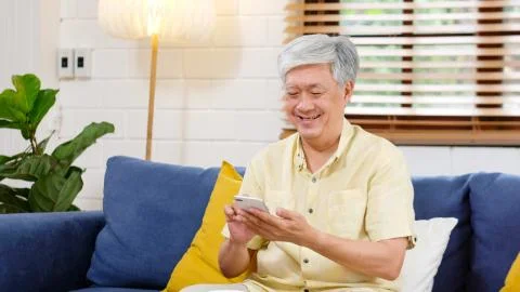 Senior asian man using mobile phone at home living room background, Happy ret Stock Photos