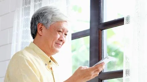 Senior asian man using mobile phone at home living room background, Happy ret Stock Photos