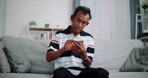 Senior Asian man using smartphone on sofa in living room at home. Stock-Footage 315861756