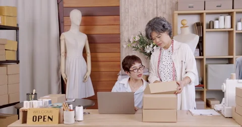 Senior asian mother checking packaging box with adult daughter using laptop Stock Footage 326421206