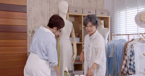 Senior asian mother smiling while using measuring tape on mannequin beside Stock Footage 326426632