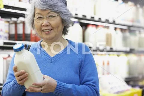 Senior Asian Woman Holding Milk In Grocery Store