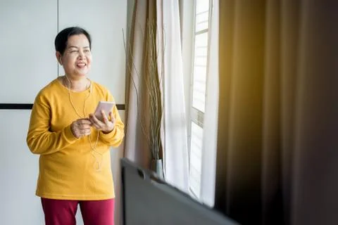 Senior asian woman listening to music with earphone,Elderly female using mobi Stock Photos