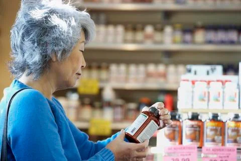 Senior Asian woman reading vitamin label Stock Photos