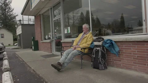 Senior backpacker with a yellow raincoat resting on a bench Stock Footage 331655278