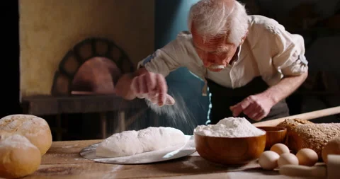Senior bakery worker putting flour on bread dough and forming a loaf, putting Stock Footage 154176331