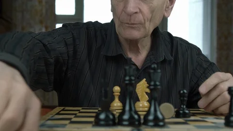 Senior bald man arranges chess pieces on wooden chessboard Stock Footage 126766241