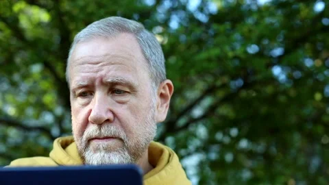 Senior bearded man using tablet for communication looking at screen resting outd 스톡 동영상 142314207