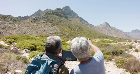 Senior biracial couple in mountains using tablet, in slow motion Stock Footage 234350473