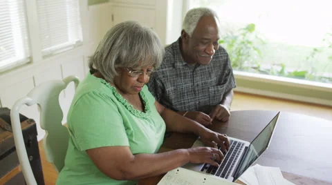 Senior black couple using laptop to do online banking Видео 51216787