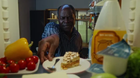 Senior Black Man Breaking Diet by Taking Sweet Cake from Fridge Stock Footage 342255582