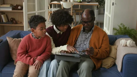 Senior Black Man Learning from Children to Pay Online via Tablet at Home Stock Footage 322525658