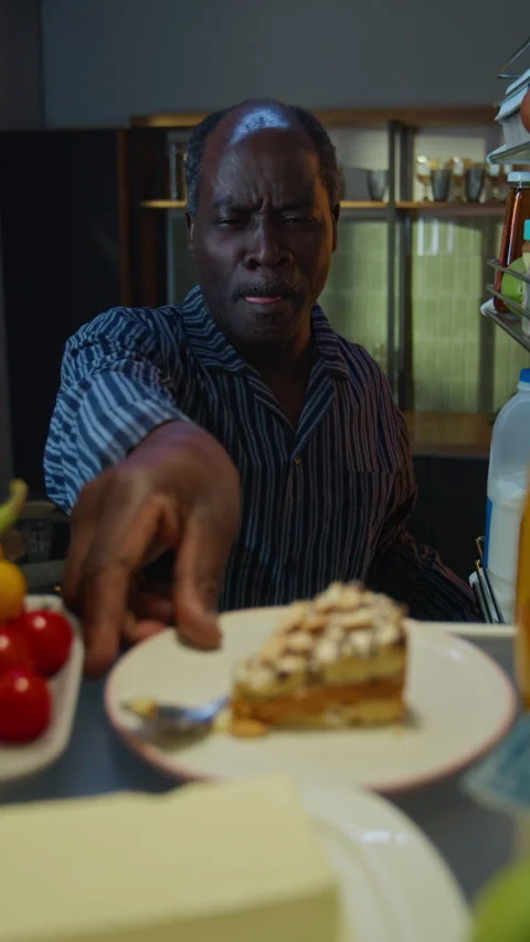 Senior Black Man Taking Cake from Fridge at Night Stock Footage 342257547